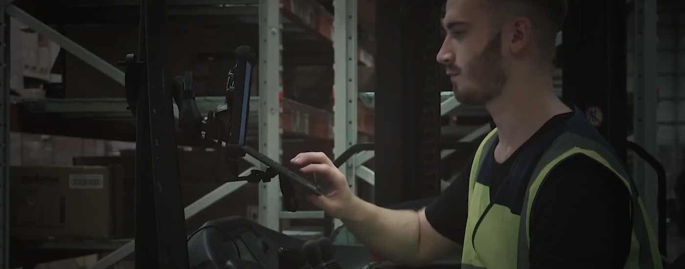 A man in a warehouse with a tablet on forklift