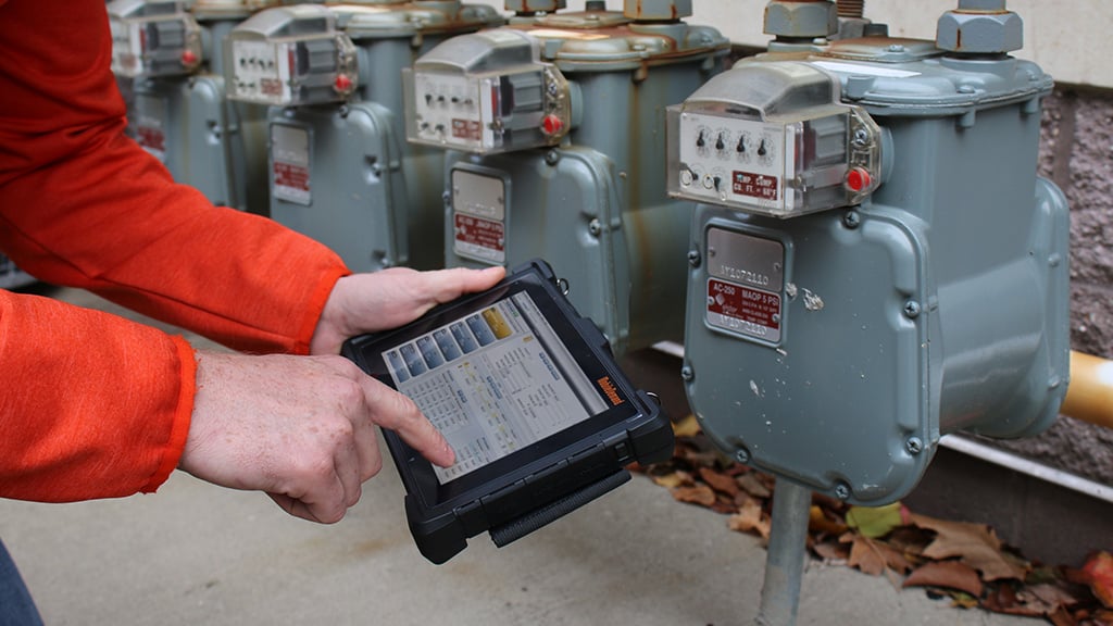 person holding rugged tablet next to electrical meter