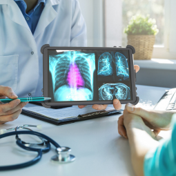 Doctor holding rugged tablet showing image of chest xray to patient